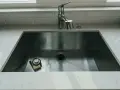 Nowoczesny zlew kuchenny ze stali nierdzewnej z baterią i gąbką.