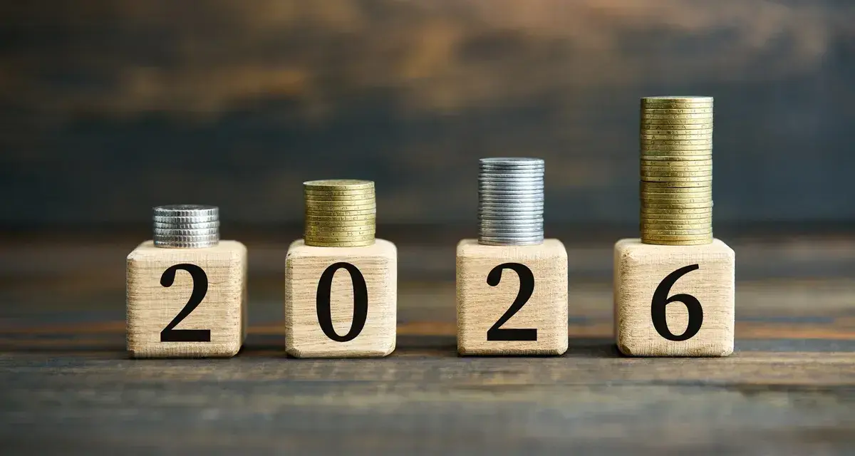Drewniane klocki z cyframi 2026 i stosy monet.