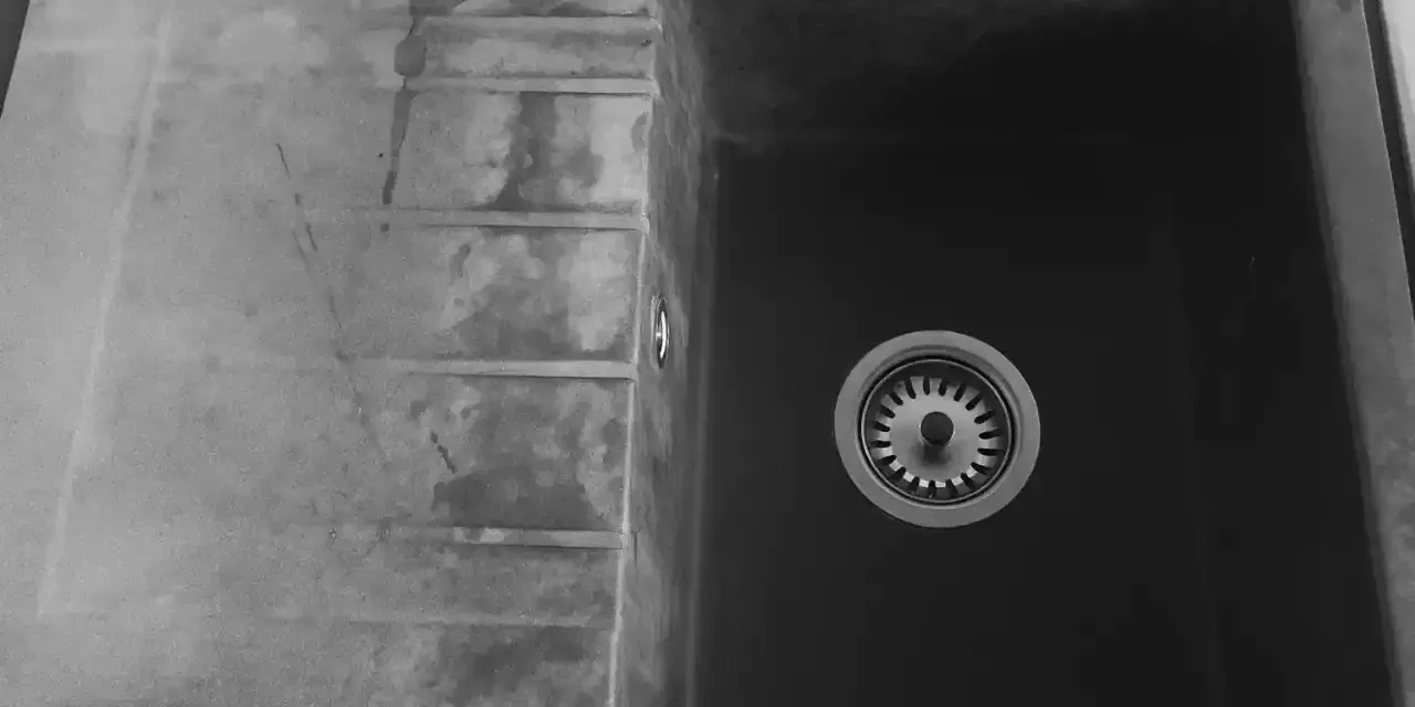 Czarny zlew granitowy z ociekaczem i baterią.