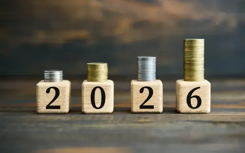 Drewniane klocki z cyframi 2026 i stosy monet.