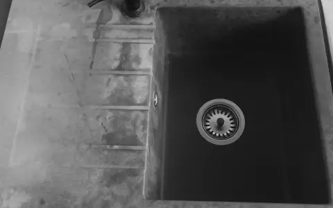 Czarny zlew granitowy z ociekaczem i baterią.