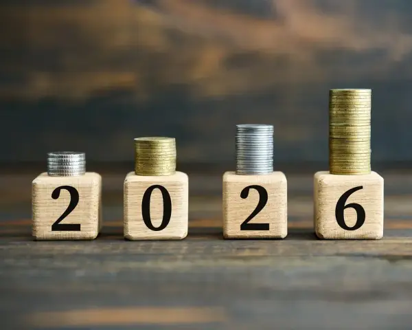 Drewniane klocki z cyframi 2026 i stosy monet.