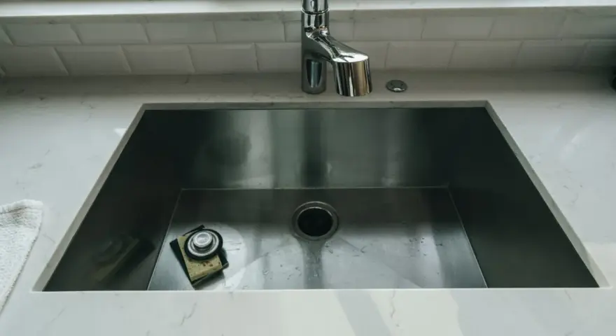 Nowoczesny zlew kuchenny ze stali nierdzewnej z baterią i gąbką.